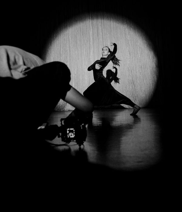 Woman performing a fluid cardio movement in a calm, dark studio environment.